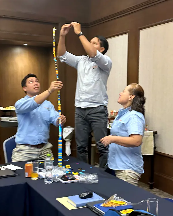Participantes armando una torre en un ejercicio práctico de trabajo en equipo