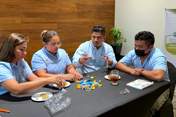 Equipo realizando un ejercicio práctico con piezas en mesa de trabajo