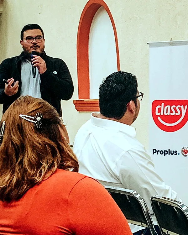 Ray Marfil presentando con micrófono junto a un banner de Classy