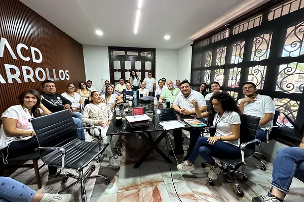 Sesión de capacitación en sala con letrero de ACD Desarrollos